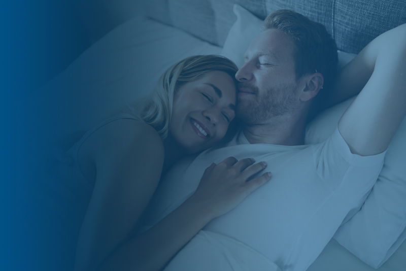 Woman holding man in bed happy and content
