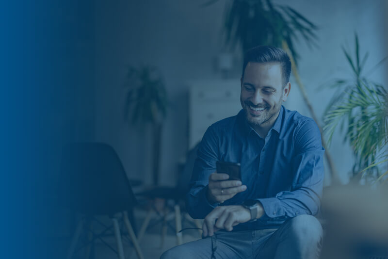 Man happy sitting down looking at mobile phone