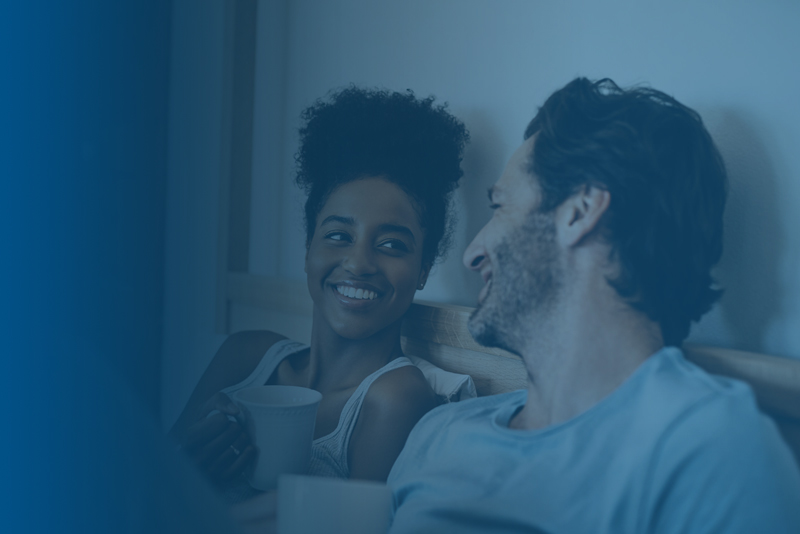 A man and woman talking in bed being happy